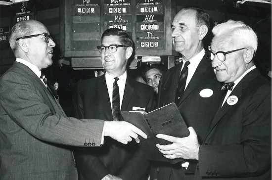 Stan Avery, Russ Smith and the president of the New York Stock Exchange watch as the company’s symbol appears on the electronic board of the NYSE for the first time.